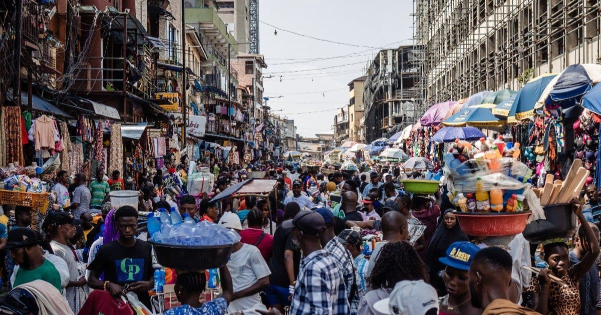 A bustling Lagos market street full of traders and shoppers